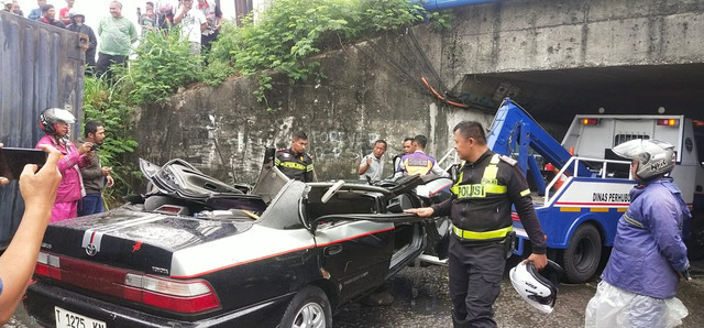 Petugas evakuasi mobil sedan Toyota Corolla "Greco" yang tertimpa truk kontainer. Foto: Dok. kumparan