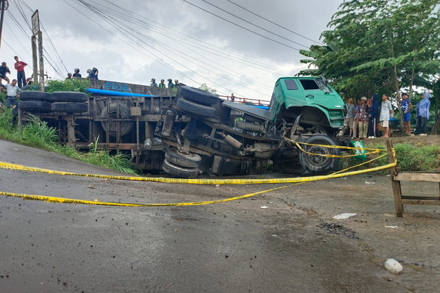 Truk kontainer yang terguling di akses jalan irigasi Desa Kondangjaya, Kecamatan Karawang Timur, Karawang, Senin (16/2/2026). Foto: kumparan
