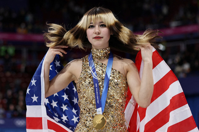 Peraih medali emas Alysa Liu dari Amerika Serikat merayakan kemenangannya dengan bendera nasionalnya setelah memenangkan Seluncur Tunggal Putri pada Olimpiade Milano Cortina 2026 di Arena Seluncur Es Milano, Milan, Italia, Kamis (19/2/2026). Foto: Amanda Perobelli/REUTERS
