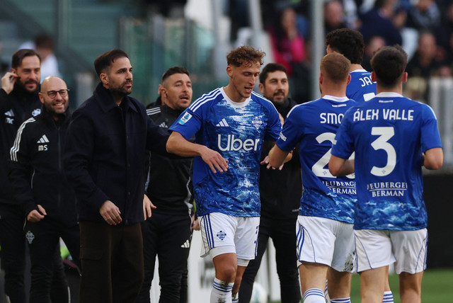 Mergim Vojvoda dari Como merayakan gol pertama mereka bersama pelatih Cesc Fabregas dan rekan setimnya pada pertandingan Liga Italia antara Juventus vs Como di Stadion Allianz, Turin, Italia, Sabtu (21/2/2026). Foto: Ciro De Luca/REUTERS