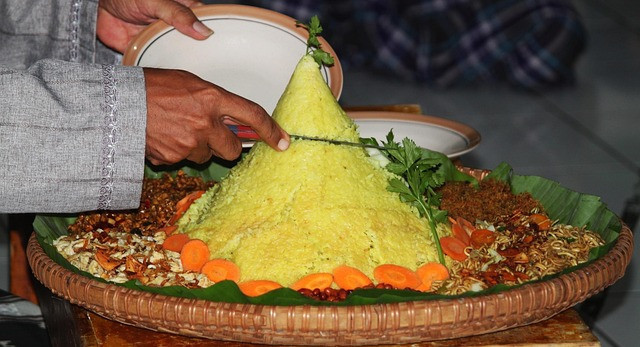 Pelaksana upacara Ujungan khas Banjarnegara sedang memotong tumpeng yang dihidangkan. Sumber foto: pixabay.com