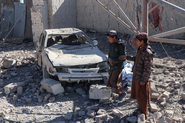 Anak-anak Afghanistan berjalan melewati mobil yang rusak setelah serangan udara Pakistan di desa Balish, distrik Urgun, Provinsi Paktika, Pakistan, Minggu (22/2/2026). Foto: AFP