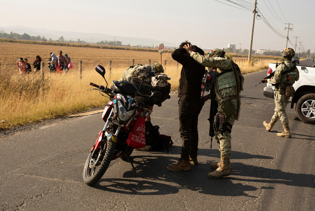 Tentara memeriksa pengendara sepeda motor setelah kejahatan terorganisir membakar kendaraan untuk memblokir jalan menyusul operasi federal di mana sumber pemerintah mengatakan gembong narkoba Meksiko Nemesio Oseguera. Foto: REUTERS/Gabriel Trujillo