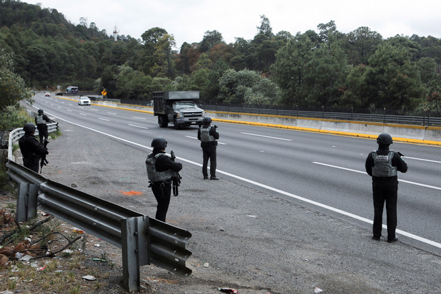 Anggota Garda Nasional berjaga di pos pemeriksaan di jalan raya yang menghubungkan Kota Meksiko dengan negara bagian Puebla, menyusul penghalang jalan dan serangan pembakaran yang dilakukan oleh anggota kejahatan. Foto:  REUTERS/Paola Garcia