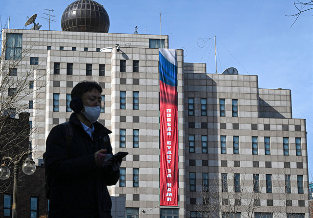 Seorang pria berjalan di depan kedutaan Rusia di Seoul yang dipasangi spanduk bertuliskan "Kemenangan akan menjadi milik kita" pada 23 Februari 2026. Foto: Jung Yeon-je / AFP