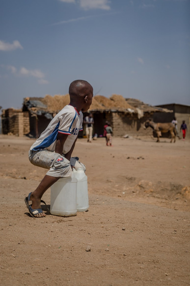 Seorang anak Malawi sedang membawa dua jerigen untuk menampung air. Foto: Daniel Mtombosola/Unsplash