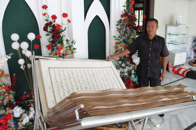 Satpam menunjukkan Alquran raksasa koleksi Museum Jenang dan Gusjigang, Kabupaten Kudus, Jawa Tengah yang selama Ramadan diletakkan di Masjid Agung Kudus. Foto: Vega Maarijil Ula/kumparan