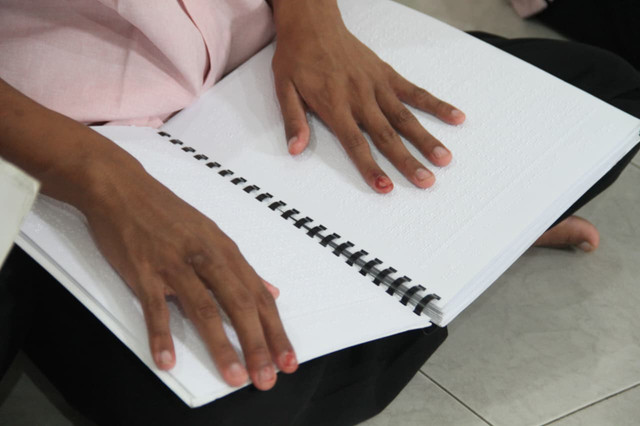 Tangan disabilitas sensorik netra di Panti Pelayanan Sosial Pendowo Dinsos Jateng meraba Al-Quran Braille. Foto: Vega Ma'arrijil Ula/kumparan