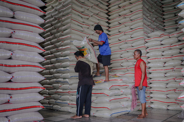 Kuli panggul mengangkut karung beras seberat 50 kilogram saat memuatnya ke mobil di komplek pergudangan Food Station Tjipinang Jaya, Jakarta Timur, Jumat (27/2/2025). Foto: Jamal Ramadhan/kumparan