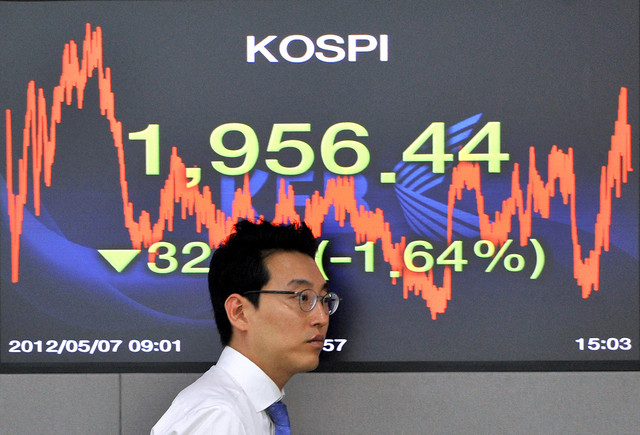 Seorang pekerja melintasi layar yang menampilkan Indeks Harga Saham Komposit Korea di ruang perdagangan di Bank Bursa Korea di Seoul pada 7 Mei 2012. Foto: Jung Yeon-je / AFP