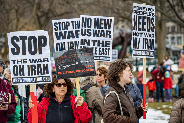 Para demonstran memegang spanduk menentang perang di Iran selama pawai Hari Perempuan Internasional menentang fasisme di taman Boston Common di Boston, pada 8 Maret 2026. Foto: Joseph Prezioso / AFP