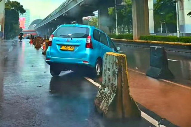 Sebuah taksi terperosok ke dalam galian pembatas jalan bekas proyek Jakarta Monorail Project di Jalan HR Rasuna Said, pada Minggu (8/3/2026) pagi. Foto: @dki360/Instagram