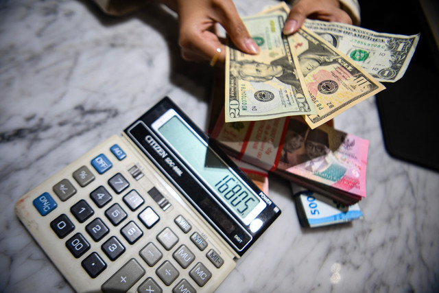 Petugas menunjukkan pecahan mata uang dolar Amerika Serikat dan mata uang Rupiah di Kantor Cabang BNI Pasar Baru, Jakarta, Selasa (10/3/2026). Foto: Muhammad Adimaja/ANTARA FOTO