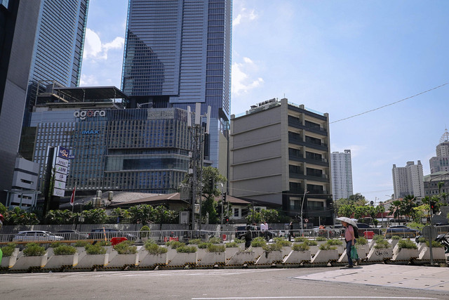 Warga menggunakan payung saat berjalan di trotoar kawasan Jalan Jenderal Sudirman, Jakarta, Senin (16/3/2026). Foto: Jamal Ramadhan/kumparan