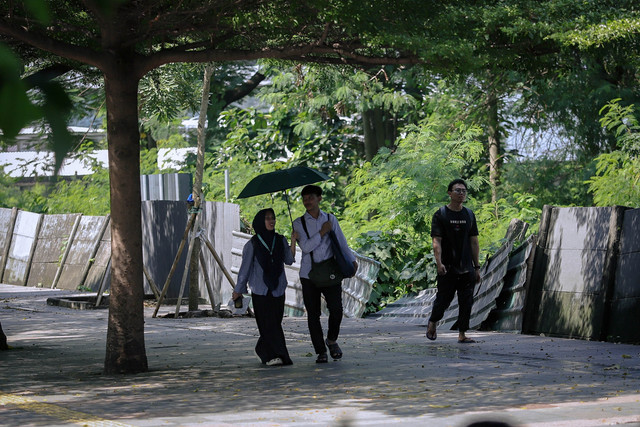 Warga menggunakan payung saat berjalan di trotoar kawasan Jalan Jenderal Sudirman, Jakarta, Senin (16/3/2026). Foto: Jamal Ramadhan/kumparan