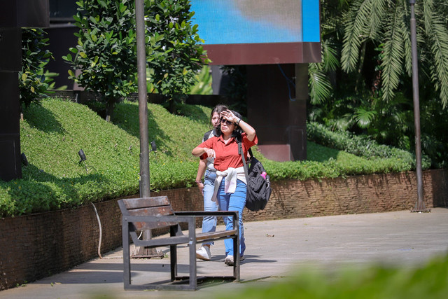 Warga menggunakan payung saat berjalan di trotoar kawasan Jalan Jenderal Sudirman, Jakarta, Senin (16/3/2026). Foto: Jamal Ramadhan/kumparan
