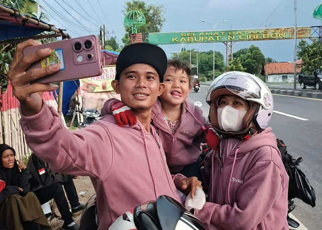Andri dan keluarganya pemudik dengan tujuan Pemalang saat berswafoto dengan latar belakang Gapura Selamat Datang di Kabupaten Cirebon. (19/3/2026). Foto: Panji Asmara/kumparan