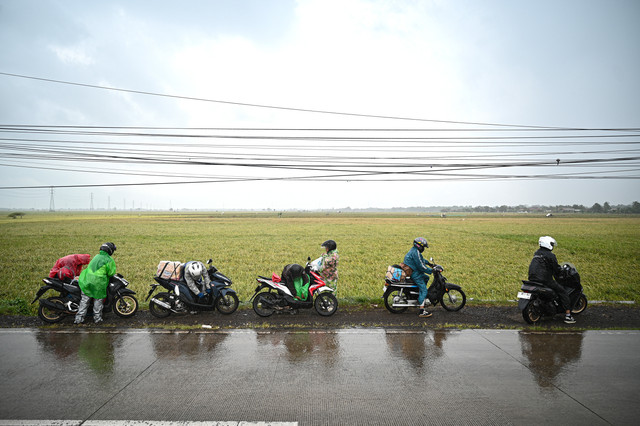 Sejumlah pemudik arus balik sepeda motor berhenti untuk mengenakan jas hujan Jalan Pantura, Kabupaten Subang, Jawa Barat, Rabu (25/3/2026).  Foto: Fauzan/ANTARA FOTO