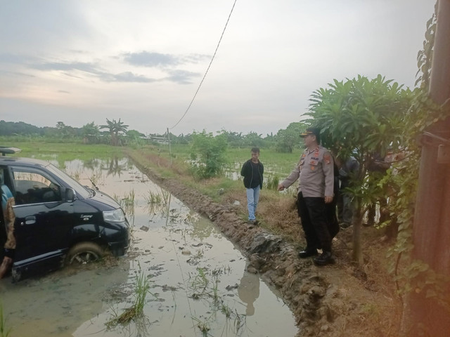 Mobil Suzuki APV luxury berwarna hitam terperosok ke sawah di Jalan Raya Babelan, Kebalen, Kecamatan Babelan, Kabupaten Bekasi, Kamis, (26/3/2026). Foto: Dok. Polsek Babelan