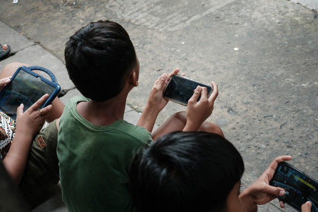 Ilustrasi - Anak Anak Bermain Handphone. Foto: Yasuyoshi Chiba/AFP