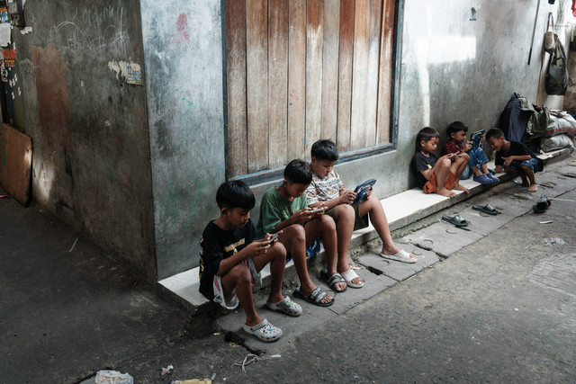 Ilustrasi - Anak Anak Bermain Handphone. Foto: Yasuyoshi Chiba/AFP