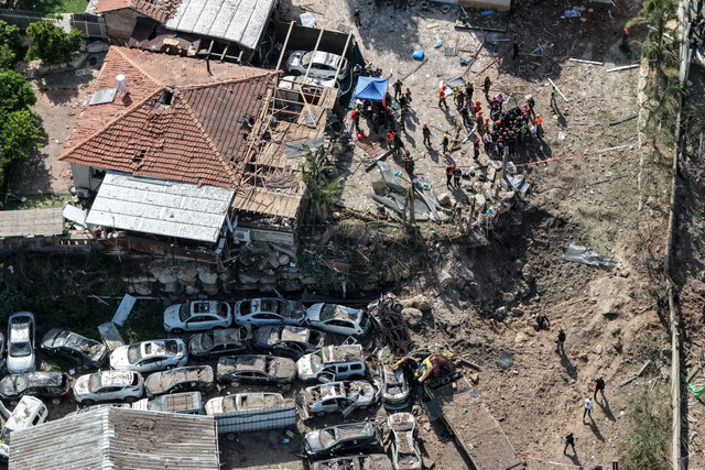 Personel keamanan dan penyelamatan berjaga di lokasi dampak serangan rudal Iran di Israel tengah, Sabtu (28/3/2026). Foto: Ilan Rosenberg/REUTERS