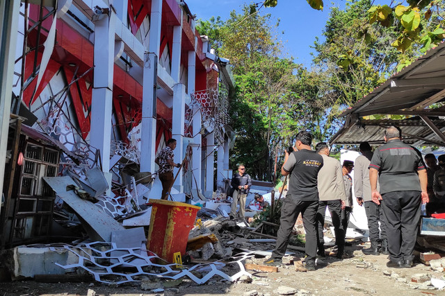 Petugas kepolisian memeriksa bangunan Komite Olahraga Nasional Indonesia (KONI) Sulawesi Utara yang rusak akibat gempa berkekuatan 7,4 magnitudo di lepas pantai Manado (2/4/2026). Foto: TONNY RARUNG/AFP