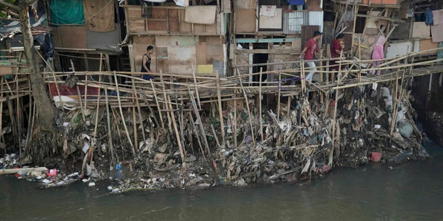 Warga melewati titian bambu di bantaran Sungai Ciliwung. Sumber: Agus Susanto Via Kompas.id