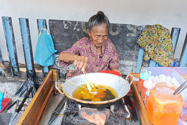 Nenek Kasini menggoreng jajan sosis dan varian lainnya di lapaknya yang berada di Desa Loram Kulon, Kecamatan Jati, Kabupaten Kudus, Kamis (2/4/2026). Foto: Vega Maarijil Ula/kumparan