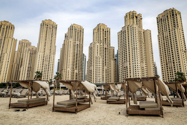 Hamparan tempat tidur pantai terlihat kosong di depan deretan gedung bertingkat tinggi di kawasan Jumeirah Beach Residence, Dubai, mencerminkan suasana sepi di area wisata tersebut pada Selasa (11/3/2026). Foto: Fadel Senna/AFP