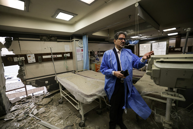 Seorang dokter menunjukkan kerusakan di dalam Rumah Sakit Gandi, yang terkena serangan pada 1 Maret, ketika sebuah proyektil menghantam menara komunikasi TV pemerintah (tengah) dan bangunan-bangunan di dekatnya di ibu kota Teheran, (2/3/2026). Foto: Atta Kenare/AFP