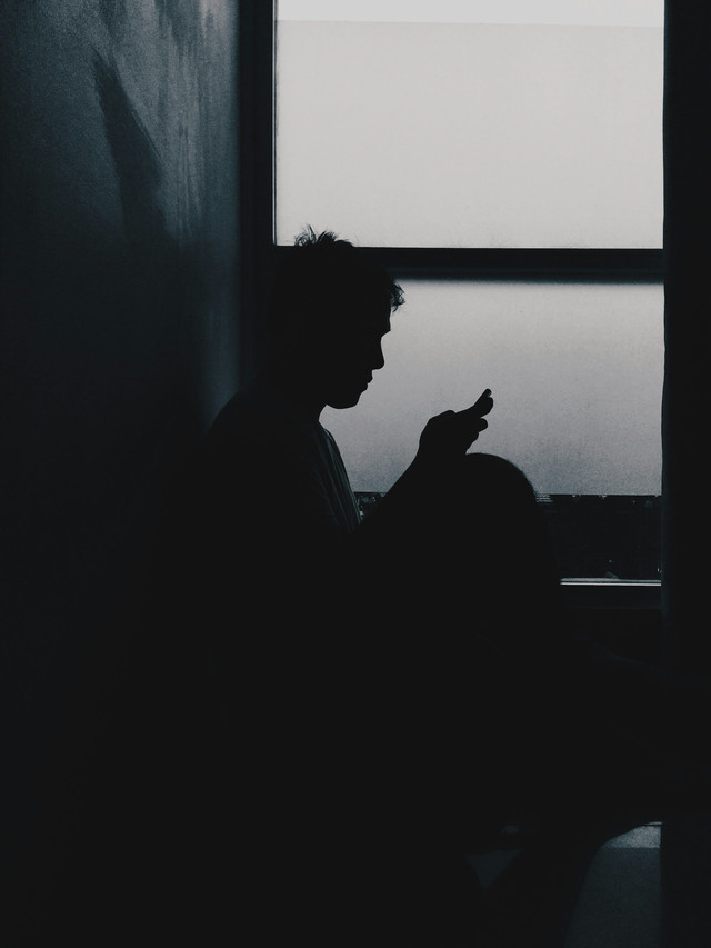 https://unsplash.com/photos/a-man-sitting-in-a-dark-room-looking-at-his-cell-phone-kUIj7skp5KM