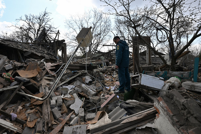 Petugas darurat berdiri di antara puing-puing rumah yang hancur setelah serangan udara di Yasynuvata, wilayah Donetsk Ukraina yang dikuasai Rusia, Sabtu (11/4/2026). Foto: AFP
