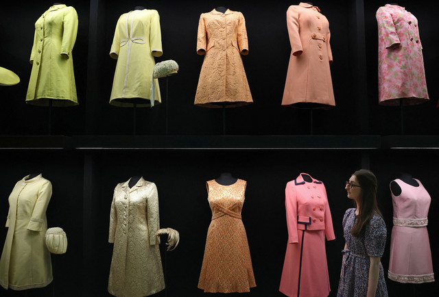 Seorang anggota staf Royal Collection Trust berpose dengan barang-barang di bagian busana Inggris dalam pameran "Queen Elizabeth II: Her Life in Style" di Istana Buckingham, London, Inggris (9/4/2026). Foto: Reuters/Toby Melville TPX