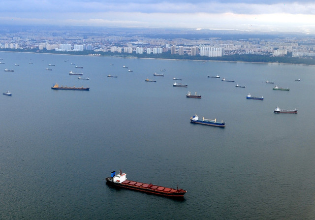 Pemandangan udara sebuah kapal yang melintas di depan jajaran kapal yang sedang berlabuh di sepanjang pesisir Singapura, tepat di mulut Selat Malaka, Minggu (23/03/2008). Foto: Roslan RAHMAN / AFP