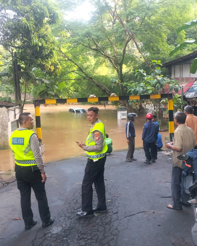 Polisi berada di lokasi kejadian sebuah mobil terjebak banjir akibat nekat melintasi genangan air di Jl. Bandung, Kelurahan Cinere, Kecamatan Cinere, Depok. Senin (20/4/2026). Foto: Istimewa