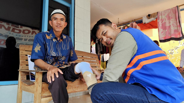 Relawan DT Peduli saat sedang memasangkan kaki palsu kepada Pak Husin (Sumber : DT Peduli)