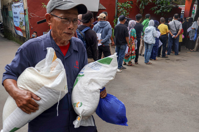 Seorang warga penerima bantuan sosial membawa beras saat penyaluran beras dan MinyaKita di Kelurahan Sukamaju, Kota Depok, Jawa Barat, Minggu (26/4/2026). Foto: Yulius Satria Wijaya/ANTARA FOTO