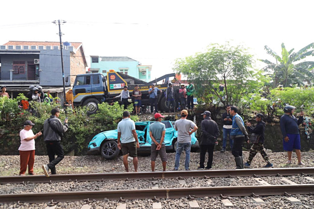 Warga mengamati kondisi taksi listrik yang rusak usai mengalami kecelakaan dengan KRL Commuter Line di Bekasi Timur, Bekasi, Jawa Barat, Selasa (28/4/2026). Foto: Iqbal Firdaus/kumparan