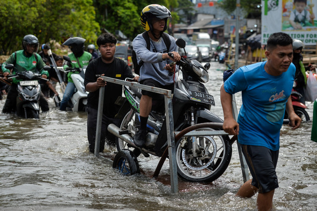 Warga menggunakan gerobak mengangkut sepeda motor dan pengendara melintasi banjir di Puri Kembangan, Jakarta, Selasa (5/5/2026). Foto: Putra M. Akbar/ANTARA FOTO 