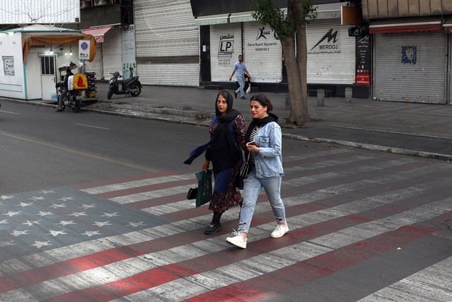 Sejumlah kendaraan tengah melintasi jalan di Kawasan Teheran pada Selasa (5/5/2026). Tampak jalanan tersebut bergambar bendera Amerika Serikat (AS) dan Israel. Foto: STR / AFP