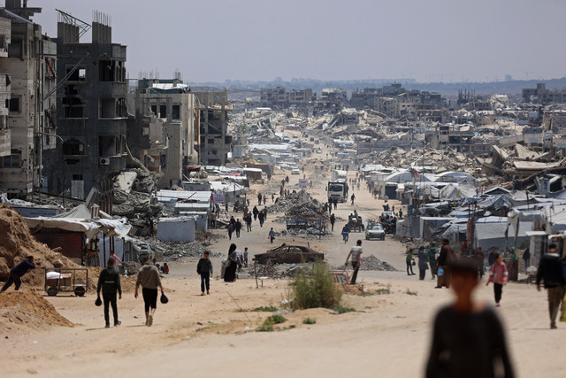 Warga Palestina yang mengungsi berjalan di sepanjang jalan dengan bangunan-bangunan yang hancur di Jabalia, Jalur Gaza utara, pada 6 Mei 2026. Foto: Omar AL-Qattaa/ AFP