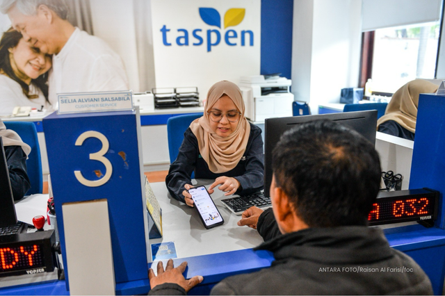 Peserta dibantu petugas TASPEN saat melakukan proses autentikasi. Foto: ANTARA FOTO/Raisan Al Farisi