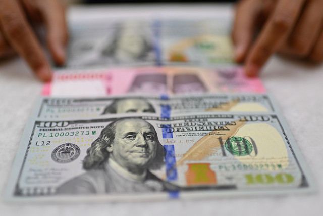 Karyawan memperlihatkan uang pecahan rupiah dan dolar Amerika Serikat (AS) di gerai penukaran mata uang asing Ayu Masagung, Jakarta, Selasa (12/5/2026). Foto: Indrianto Eko Suwarso/ANTARA FOTO