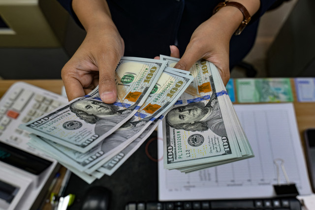 Petugas penukaran uang menghitung uang dolar AS di sebuah gerai penukaran mata uang di Jakarta (12/5/2026). Foto: Bay Ismoyo/AFP