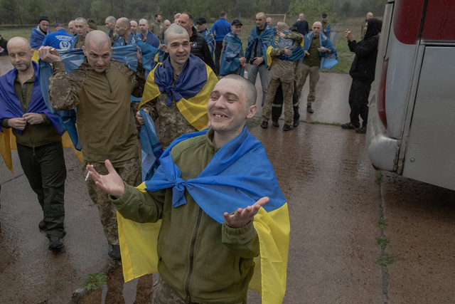 Para tawanan perang Ukraina yang dibebaskan, dibungkus dengan bendera nasional Ukraina, bereaksi setelah pertukaran tawanan di lokasi yang dirahasiakan, di wilayah Chernihiv pada 15 Mei 2026, di tengah invasi Rusia ke Ukraina. Foto: Roman Pilipey / AFP