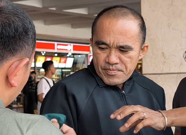 Petugas Kepolisian Bareskrim Mabes Polri memasangkan masker kepada AKP Deky Jonathan Sasiang setibanya dari Kaltim, di Terminal 2 Bandara Soekarno Hatta, Tangerang, Banten, Senin (18/5/2026). Foto: Muhammad Iqbal/ANTARA FOTO