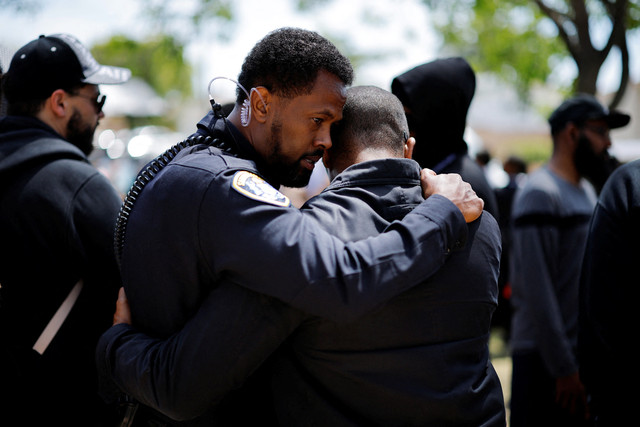 Petugas Kepolisian San Diego, Farah, menghibur seorang pria yang menghadiri konferensi pers kelompok Muslim di dekat Pusat Islam San Diego, sehari setelah insiden penembakan fatal, di San Diego, California, AS, 19 Mei 2026. Foto: REUTERS/Mike Blake