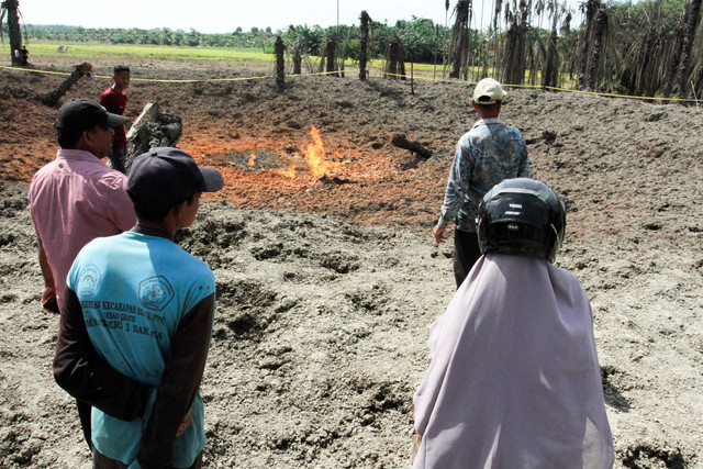 Warga mengamati sumur bor yang menyemburkan api dari dalam tanah di area perkebunan kelapa sawit Desa Blang Rubek, Kecamatan Lhoksukon, Aceh Utara, Aceh, Jumat (22/5/2026). Foto: Rahmad/ANTARA FOTO
