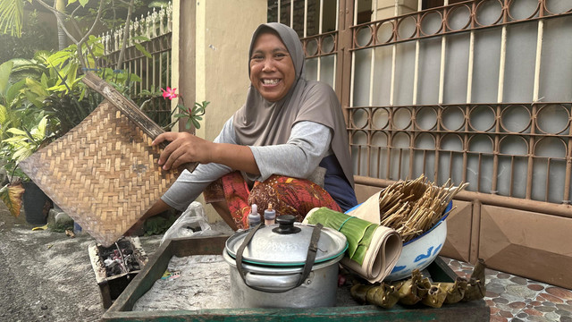 Siti Hasinah atau Mbak Siti (51), penjual sate keliling asal Madura, berjalan kaki menyusuri perumahan di Madiun untuk menawarkan dagangannya, Kamis (21/05/2025). Foto: Calya/kumparan.